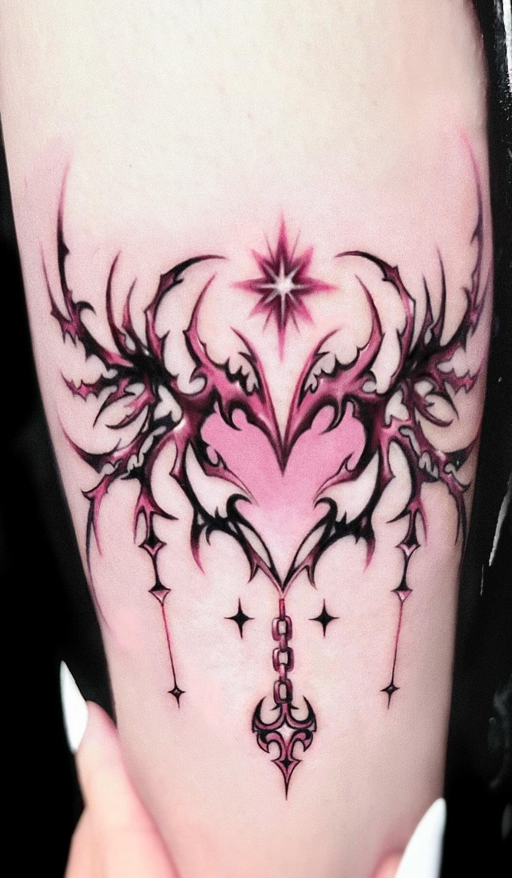 Heart tattoo with flame wings and a star on a person's arm.