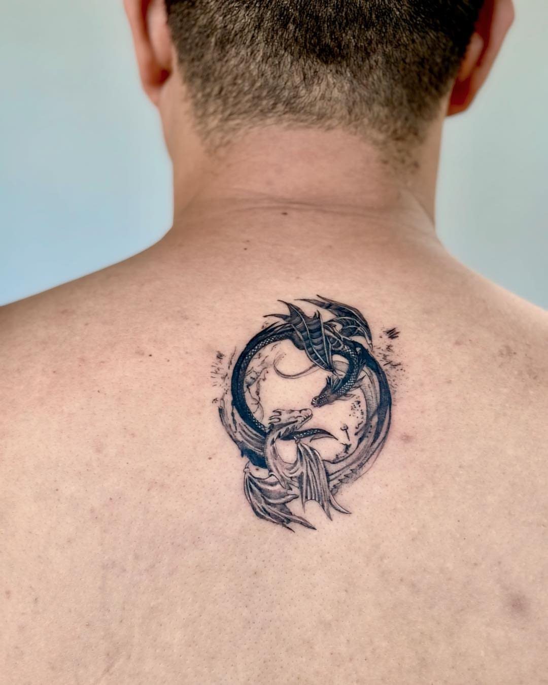 Yin yang tattoo featuring two dragons on a person's upper back.