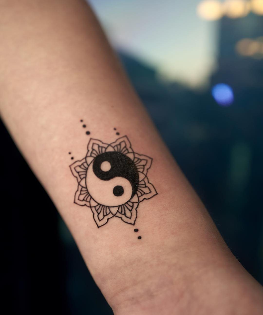 Yin yang symbol inside a detailed mandala flower tattoo on a forearm